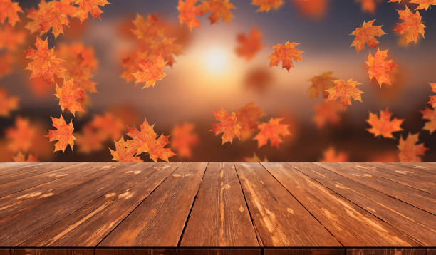 istock Idyllic blurred autumn landscape with fall leaves and empty wooden table 1424333496