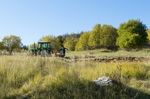 Land cultivation with tractor, agricultural field near the forest, rural landscape, in Gorski kotar, Croatia