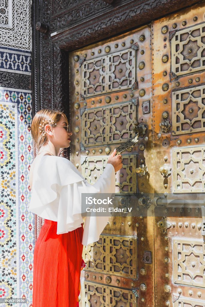 young woman at door of mosque young woman at door of mosque, dressed in red skirt and white blouse, about to knock on the door. Adult Stock Photo
