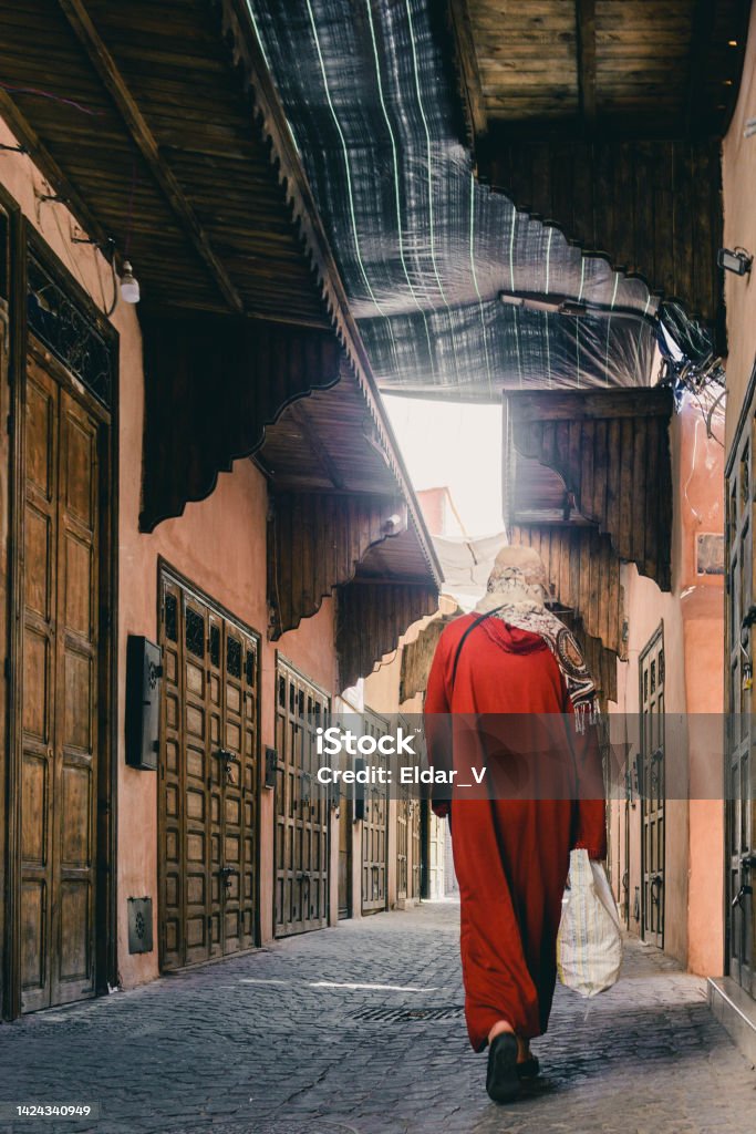 woman in red tunic woman in red tunic, walking through the streets of a city in morocco. Adult Stock Photo