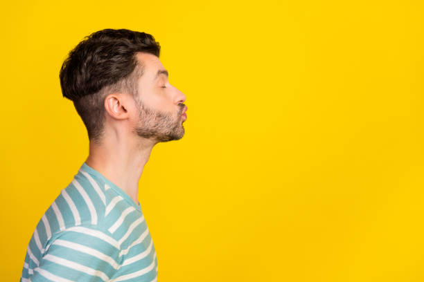 Profile photo of romantic guy kiss promo wear striped t-shirt isolated on yellow color background Profile photo of romantic guy kiss promo wear striped t-shirt isolated on yellow color background. blowing a kiss stock pictures, royalty-free photos & images