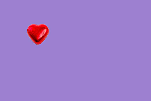 istock Red chocolate heart on the side on violet background. 1424342750
