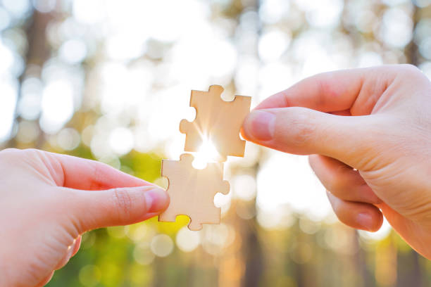 istock Hands matching jigsaw puzzle pieces at sunset 1424344017