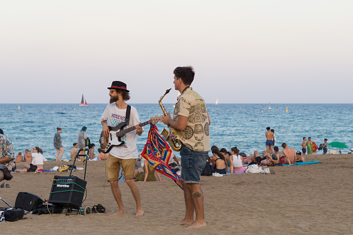 Barcelona, Catalonia, Spain; July 20th 2022: Street musicians playing bass and saxophone on the beach.
