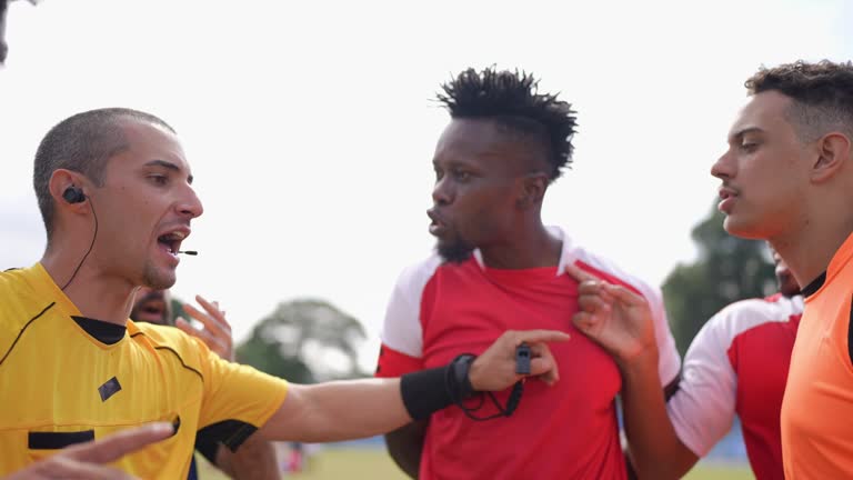 Referee gesturing to check VAR and players complaining during soccer match