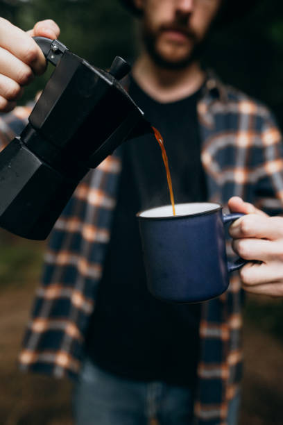 istock The man pouring a coffe into a mug in the camping 1424357800