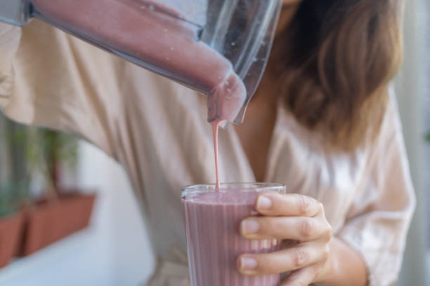 istock Young woman pours a breakfast smoothie into a glass 1424371007