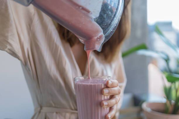 istock Young woman pours a breakfast smoothie into a glass 1424371009