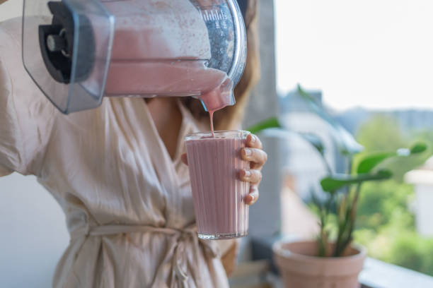 Young woman pours a breakfast smoothie into a glass stock photo