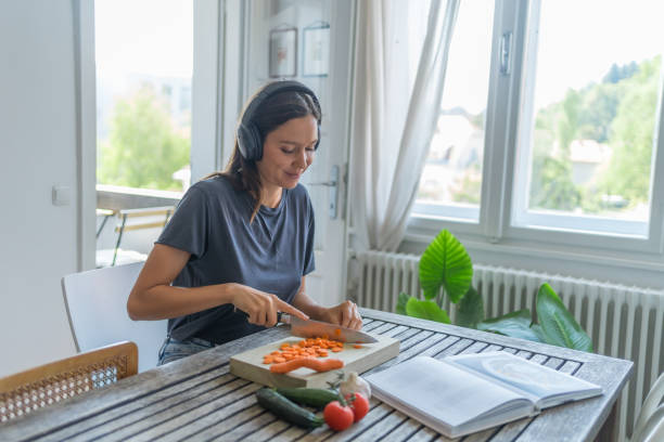 istock Young woman listens to audio recording while cooking 1424371420