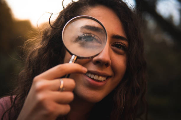 目の上に虫眼鏡をかざした微笑む白人少女 - magnifying glass lens holding europe ストックフォトと画像