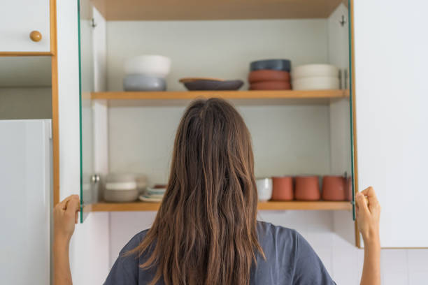 istock Young woman opens cupboard for dishes 1424371508