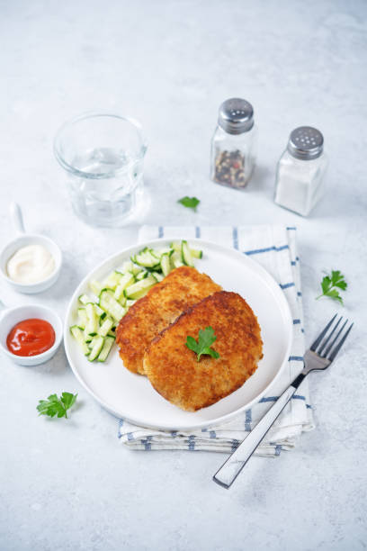 istock Fresh prepared schnitzel in a plate with fresh cucumber slices 1424372930