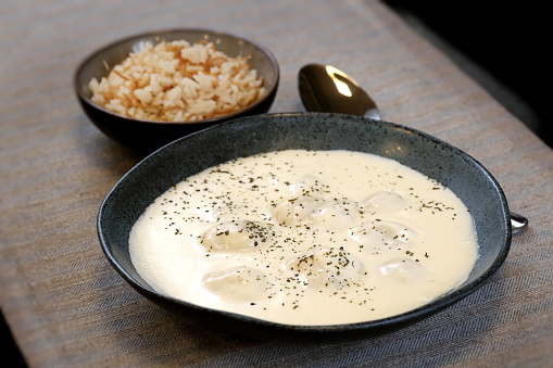 Close-up vertical shot of classic Swiss cheese fondue in hot pot, with toasted cube bread and fried beef as side dish.