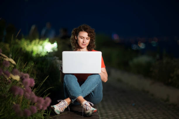 istock work from vacation, remote workers. middle aged woman using a laptop, connecting to the Internet in the summer city at sunset. Working from Anywhere. 1424373282