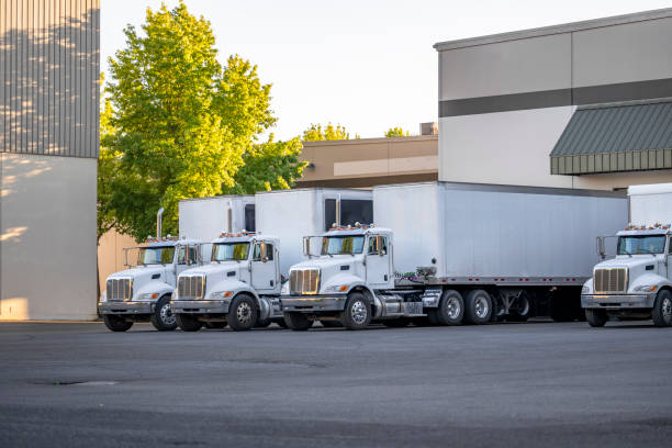 istock Middle power day cab big rig semi trucks with dry van semi trailers unloading cargo in warehouse dock 1424379620