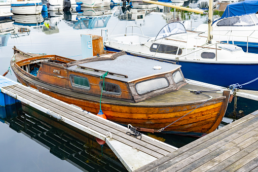 Old wooden fishingboat docked. Calm water.