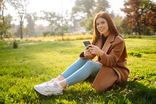 Pretty woman with smartphone having a good time in autumn weekend. People, lifestyle, relaxation and vacations concept.