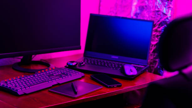 istock Creative designer's workplace, back view. Office chair and work desk view with graphic tablet, computer and smartphone. Retoucher home office in neon pink blue 1424389490