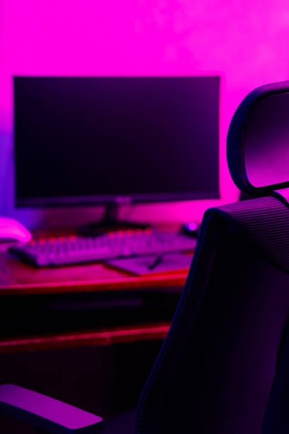 istock Creative designer's workplace, back view. Office chair and work desk view with graphic tablet, computer and smartphone. Retoucher home office in neon pink blue 1424389500
