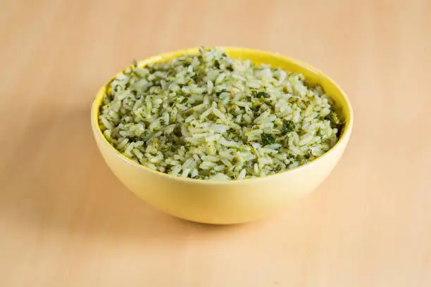 rice with broccoli in yellow bowl on wooden background, in Brazil it's called arroz de brocolis