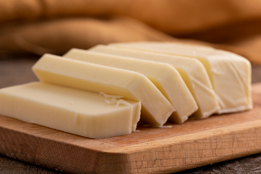 Sliced cheddar cheese on chopping board.