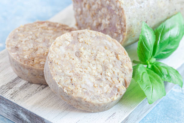Traditional Irish white or oatmeal pudding sausage slices on a wooden board, horizontal, closeup stock photo