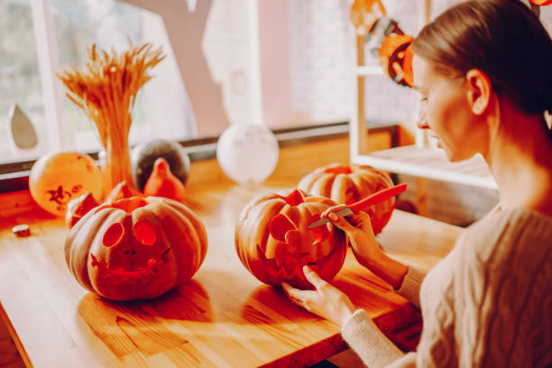 istock Young woman carving pumpkins for hallowee. 1424397631