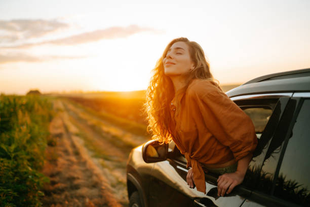 Young woman is resting and enjoying sunset in the car. stock photo