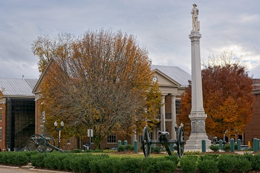 Old Williamson County Courthouse stands behind civil war era bronze canons defending monument to the soldiers who died in the Battle of Franklin on the Franklin public square in late autumn colors. .
