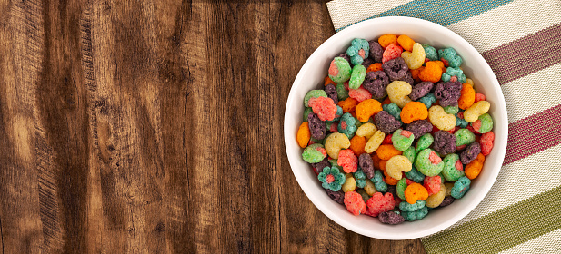 Top view of bowl with fruit cereal naturally and artificially fruit flavored sweetened corn puffs. Cereal fruity shapes