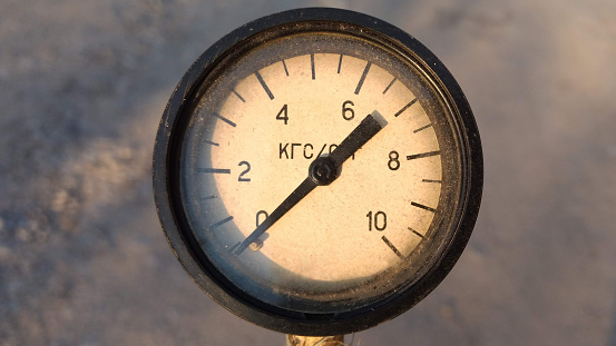 Old vintage rusty psi bar pressure measurement gauge installed on pneumatic equipment. Text in russian - kilogram-force.