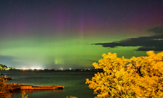 Aurora borealis of purple and green colors dancing over cottage piers in Temiskaming Shores in Northern Ontario, Canada