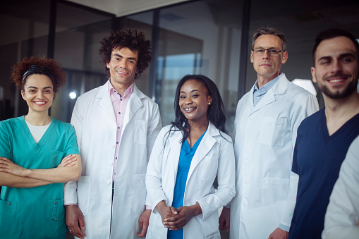 A waist-up view of a diverse group of smiling doctors.