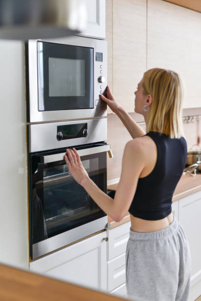femme chauffant des aliments au micro-ondes - timer cooking domestic kitchen time photos et images de collection