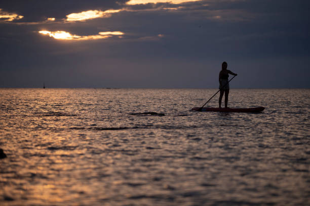 istock A woman paddles on a stand-up board. Dramatic sky 1424425597