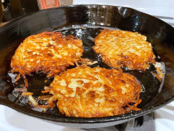 three potato latkes frying in oil - latke imagens e fotografias de stock