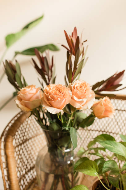 istock Soft Peach-Colored Country Roses Arranged with Rust-Colored Autumn Foliage in a Vase on a Boho Rattan Chair 1424432766