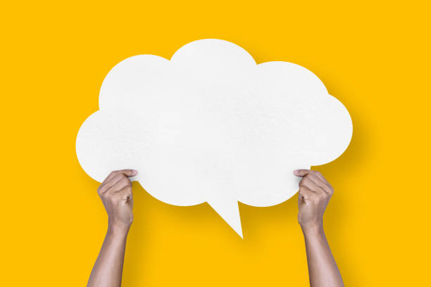 istock hand holding white paper cloud shape speech bubble balloon isolated on yellow background communication bubbles 1424444631