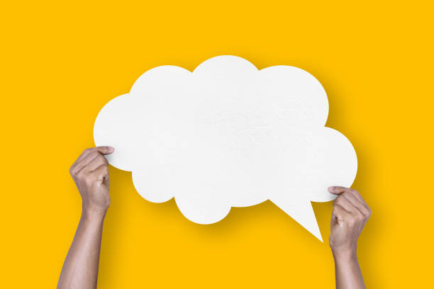 istock hand holding white paper cloud shape speech bubble balloon isolated on yellow background communication bubbles 1424444634