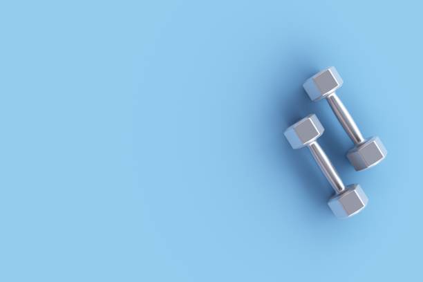 istock Two silver fitness dumbbells on blue background 1424447107
