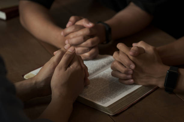 Christian group of people holding hands praying worship to believe and Bible on a wooden table for devotional or prayer meeting concept. Christian group of people holding hands praying worship to believe and Bible on a wooden table for devotional or prayer meeting concept. bible study group of people small group of people stock pictures, royalty-free photos & images