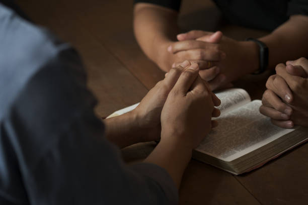 Christian group of people holding hands praying worship to believe and Bible on a wooden table for devotional or prayer meeting concept. Christian group of people holding hands praying worship to believe and Bible on a wooden table for devotional or prayer meeting concept. bible study group of people small group of people stock pictures, royalty-free photos & images