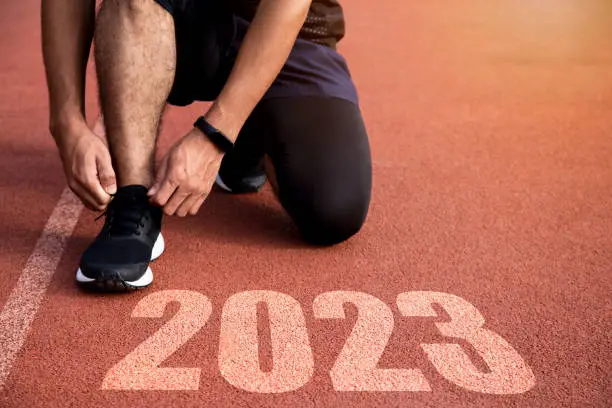 Photo of Goals and plans for the next year. Rear view of a man preparing to start on an athletics track engraved with the year 2023.
