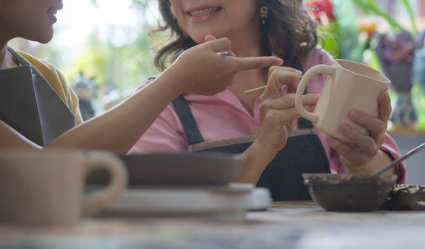 istock Smiling middle aged woman in apron creating handmade ceramic cup in a pottery. 1424457827