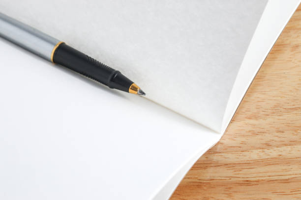 istock pen and book on wood background 1424457984