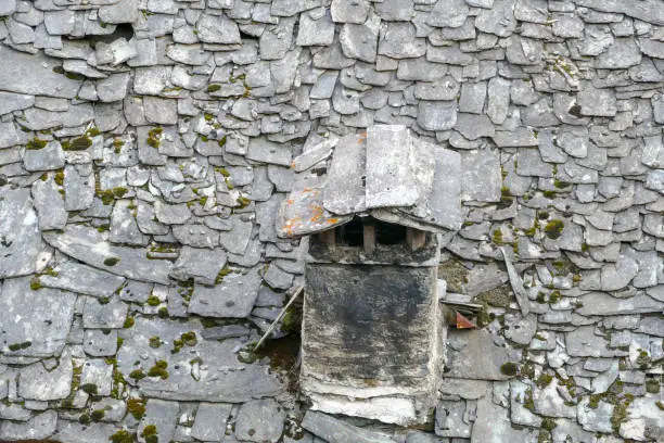 rotten roof with slate roof tiles and an old chimney, Lombardy, Italy