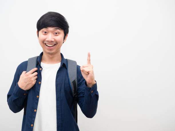 istock Asian man with school backpack smile face point finger up get idea portrait copy space white background 1424479594