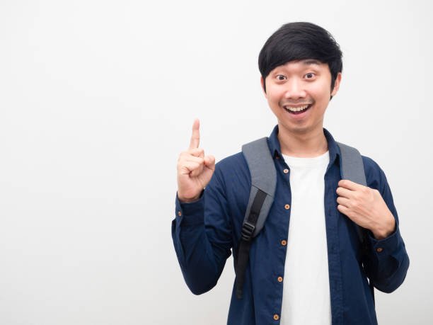 istock Asian man with school backpack smile face point finger up get idea portrait copy space white background 1424479597