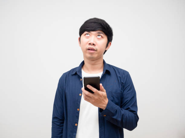 istock Asian man holding mobile phone and feeling bored gesture looking up white background 1424479812